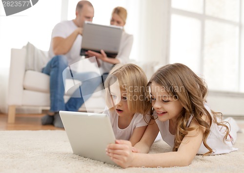 Image of smiling sister with tablet pc and parents on back