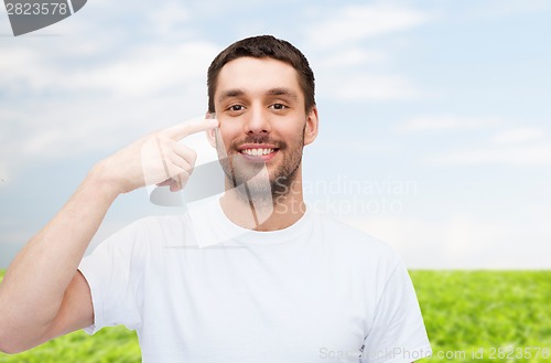 Image of smiling young handsome man pointing to eyes