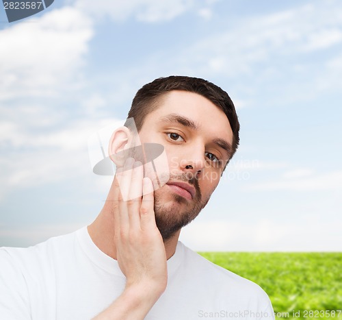 Image of beautiful calm man touching his face