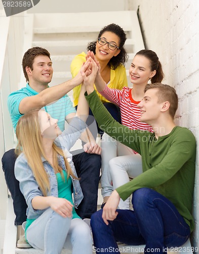 Image of smiling students making high five gesture sitting