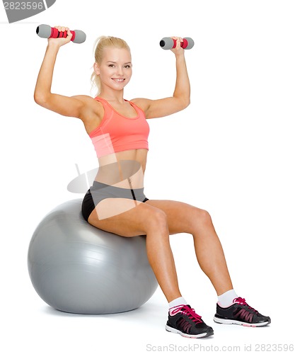 Image of woman with dumbbells sitting on fitness ball