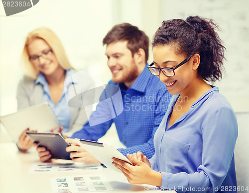 Image of smiling team with table pc and papers working