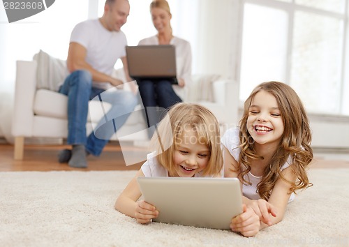 Image of smiling sister with tablet pc and parents on back