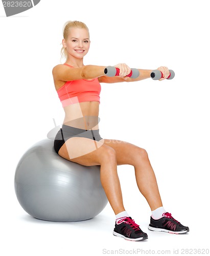 Image of woman with dumbbells sitting on fitness ball