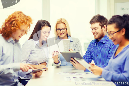 Image of smiling team with table pc and papers working