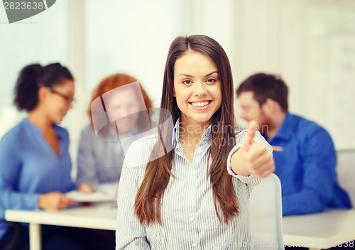 Image of smiling young businesswoman showing thumbs up