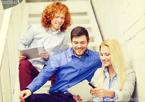 Image of team with tablet pc computer sitting on staircase