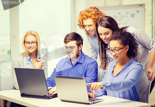 Image of smiling team with laptop computers in office