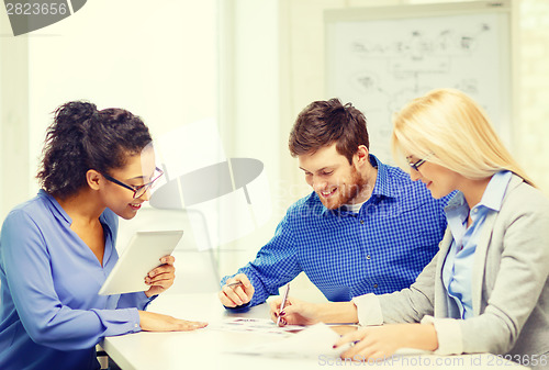 Image of smiling team with table pc and papers working