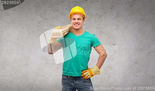 Image of smiling manual worker in helmet with wooden boards