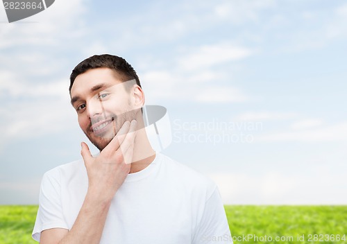 Image of beautiful smiling man touching his face