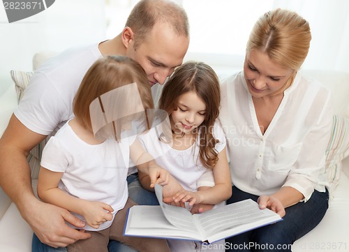 Image of smiling family and two little girls with book