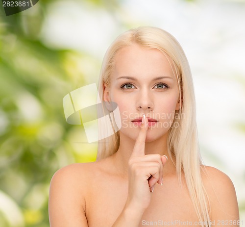 Image of calm young woman with finger on lips