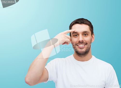 Image of smiling young handsome man pointing to forehead