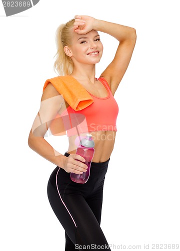 Image of smiling sporty woman with towel and water bottle