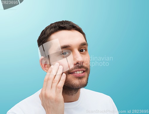 Image of beautiful smiling man touching his face