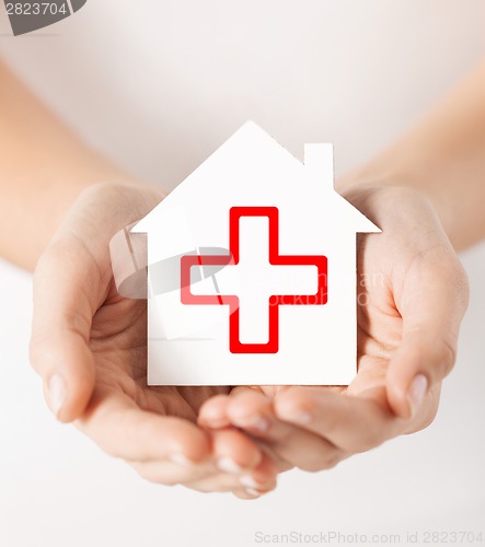 Image of hands holding paper house with red cross