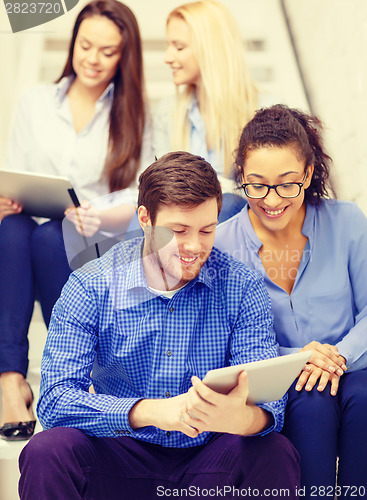 Image of team with tablet pc computer sitting on staircase