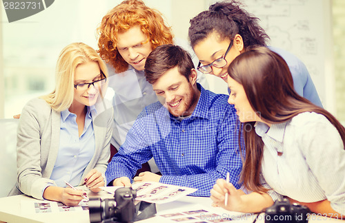 Image of smiling team with photocamera and images in office