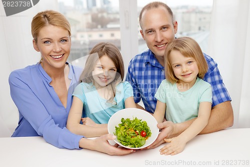Image of happy family with two kids with salad at home