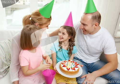 Image of smiling family with two kids in hats with cake