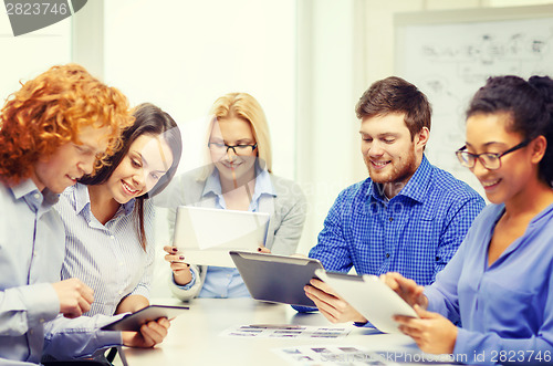 Image of smiling team with table pc and papers working