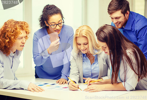 Image of smiling creative team looking over clothes designs