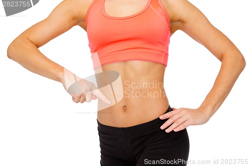 Image of close up of woman pointing finger at her six pack