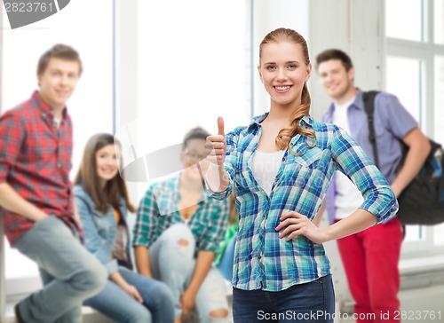 Image of young woman in casual clothes showing thumbs up