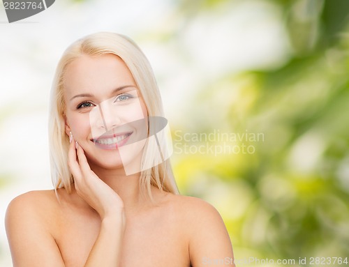 Image of smiling young woman touching her face skin