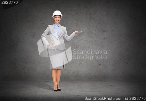 Image of businesswoman in helmet holding something on palm