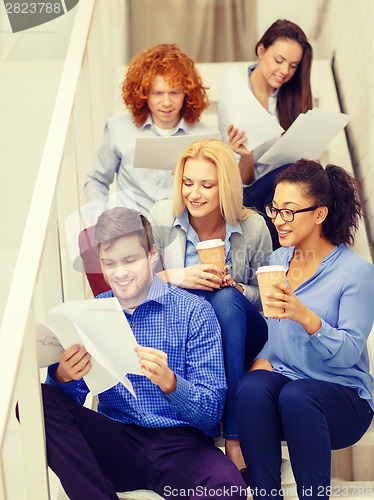 Image of team with papers and take away coffee on staircase