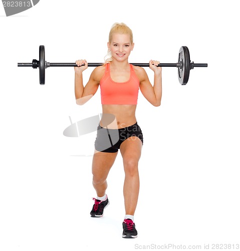 Image of smiling sporty woman exercising with barbell