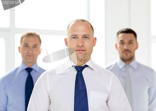 Image of serious businessman in office with team on back