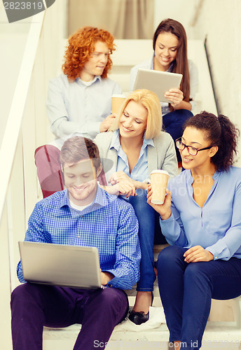 Image of team with laptop and tablet pc on staircase
