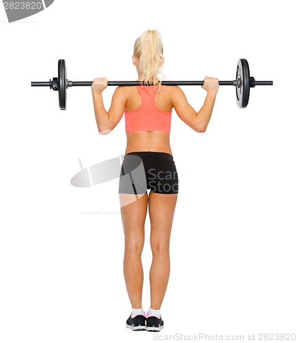 Image of sporty woman exercising with barbell from the back