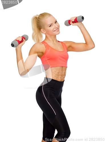 Image of smiling beautiful sporty woman with dumbbells