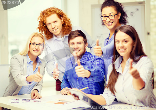 Image of creative team with papers showing thumbs up