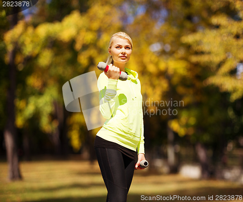 Image of sporty woman with light dumbbells outdoors