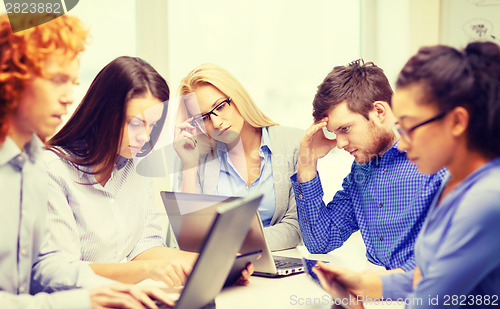 Image of depressed team with laptop and table pc computers