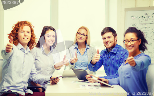 Image of smiling team with table pc and papers working