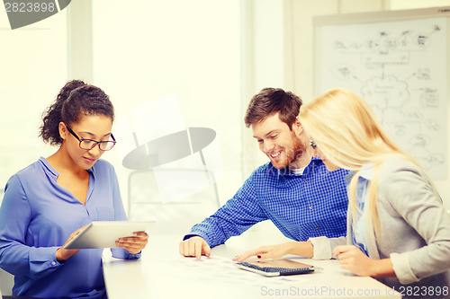 Image of smiling team with table pc and papers working