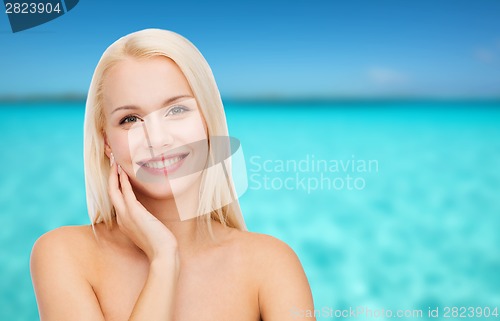 Image of smiling young woman touching her face skin