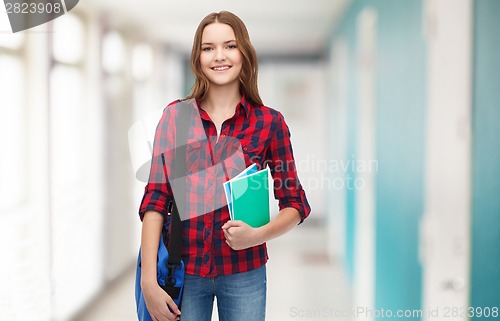 Image of smiling female student with bag and notebooks