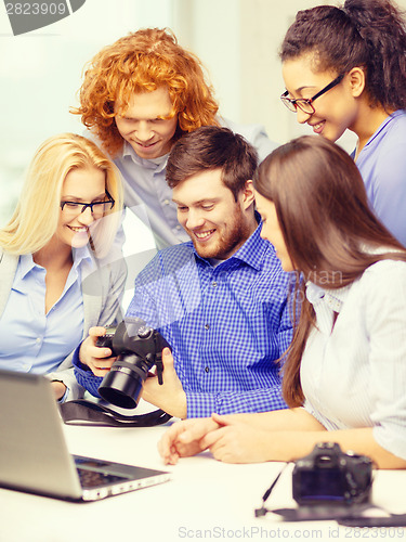 Image of smiling team with laptop and photocamera in office