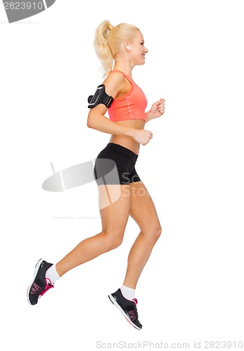 Image of sporty woman running with smartphone and earphones