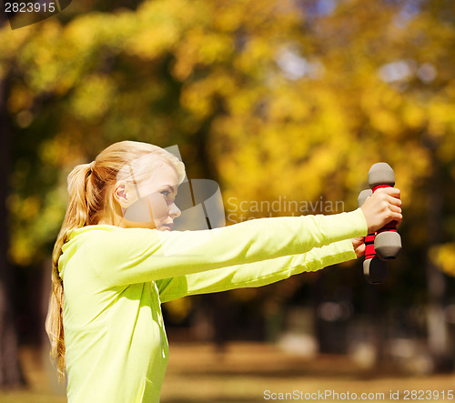 Image of sporty woman with light dumbbells outdoors