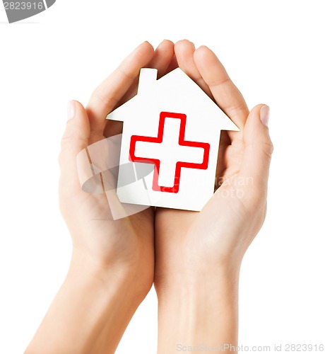 Image of hands holding paper house with red cross