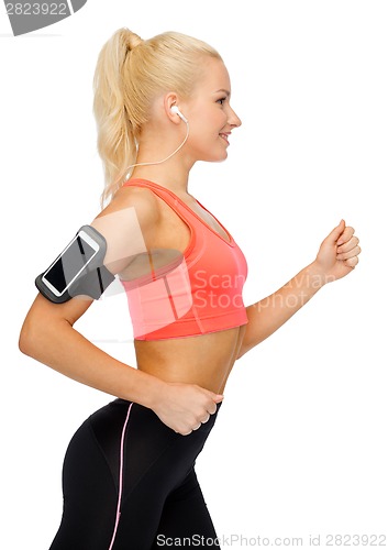 Image of sporty woman running with smartphone and earphones