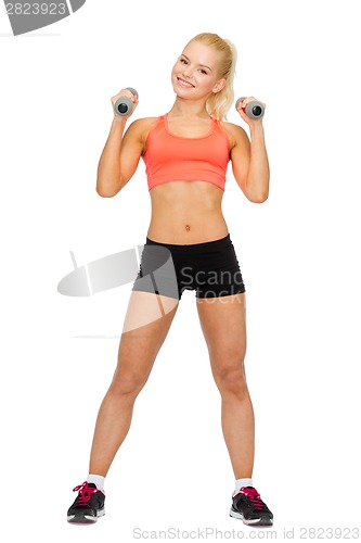 Image of smiling beautiful sporty woman with dumbbells